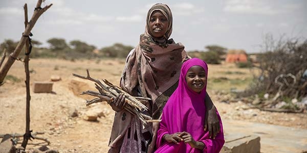 Two sisters hold firewood near their village in Somalia. Two sisters hold firewood near their village in Somalia.