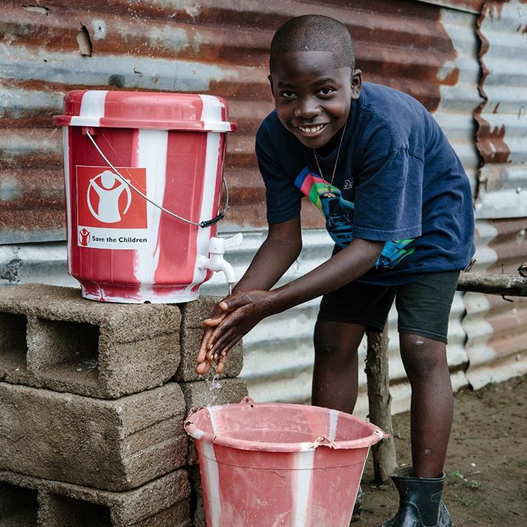A boy washes his hands using a clean water kit. A boy washes his hands using a clean water kit.