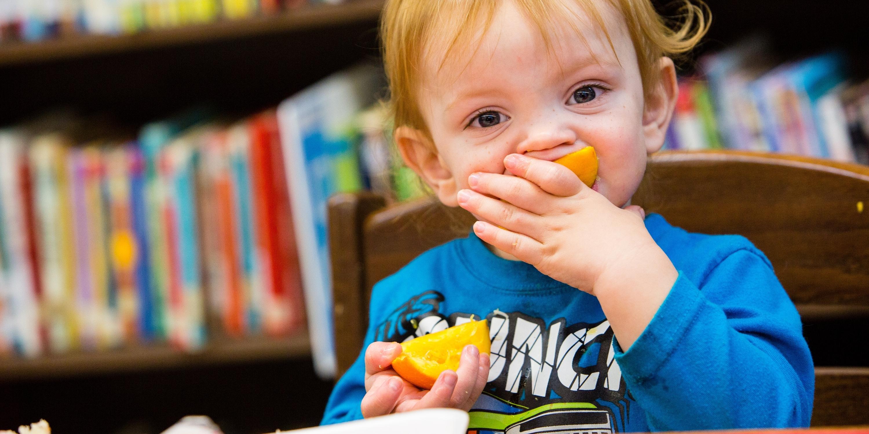 2-year-old snacks on an orange slice to promote Healthy Choices in Kentucky.