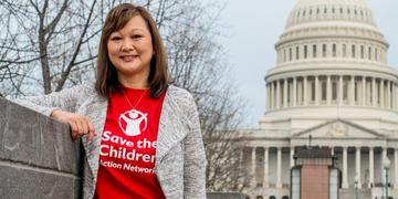 A woman wearing a red Save the Children Action Network t-shirt and stands in front of the Capitol Building in Washington D.C. Photo credit: Susan Warner/Save the Children, March 2017. A woman wearing a red Save the Children Action Network t-shirt and stands in front of the Capitol Building in Washington D.C. Photo credit: Susan Warner/Save the Children, March 2017.