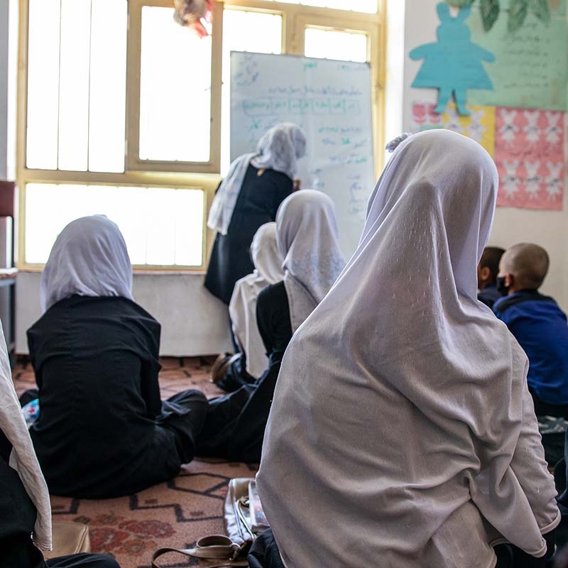 In Afghanistan, female teacher stands at the head of a classroom where boys and girls are seated. In Afghanistan, female teacher stands at the head of a classroom where boys and girls are seated.