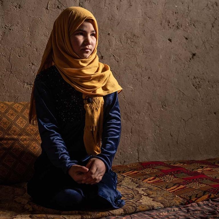 A 12-year old girl kneels on the floor of her home in a displacement camp in Afghanistan. A 12-year old girl kneels on the floor of her home in a displacement camp in Afghanistan.