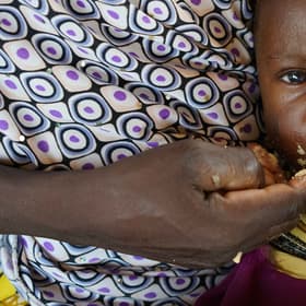 An infant of 9 months, with her mother Alima, eats high nutrient peanut paste as a distribution at the Guidanaoutchi Clinic, Niger. Photo Credit Save the Children 2016. An infant of 9 months, with her mother Alima, eats high nutrient peanut paste as a distribution at the Guidanaoutchi Clinic, Niger. Photo Credit Save the Children 2016.