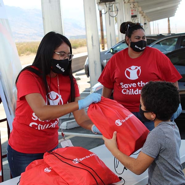 A Save the Children volunteer hands out supplies. A Save the Children volunteer hands out supplies.