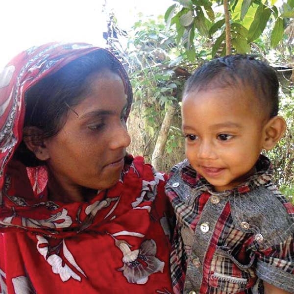 Little Hasabullah with a slight smile on his face is held by his mother in Bangladesh. Little Hasabullah with a slight smile on his face is held by his mother in Bangladesh.
