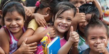 A group of smiling Bolivian children give a big “thumbs up” at an Early Childhood Development program in the village of San Ignacio de Mojos, Bolivia. There are 57 students in the school. Photo credit: Susan Warner/Save the Children, March 2016. A group of smiling Bolivian children give a big “thumbs up” at an Early Childhood Development program in the village of San Ignacio de Mojos, Bolivia. There are 57 students in the school. Photo credit: Susan Warner/Save the Children, March 2016.