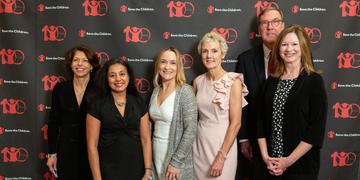 Six member of Save the Children’s Boston Leadership Council Benefit pose in front of a patterned background printed with the Save the Children logo. The men and women are attended a benefit at the Downtown Harvard Club hosted by Tim Douglas. Photo credit: Casey Atkins/Nov 2018. Six member of Save the Children’s Boston Leadership Council Benefit pose in front of a patterned background printed with the Save the Children logo. The men and women are attended a benefit at the Downtown Harvard Club hosted by Tim Douglas. Photo credit: Casey Atkins/Nov 2018.