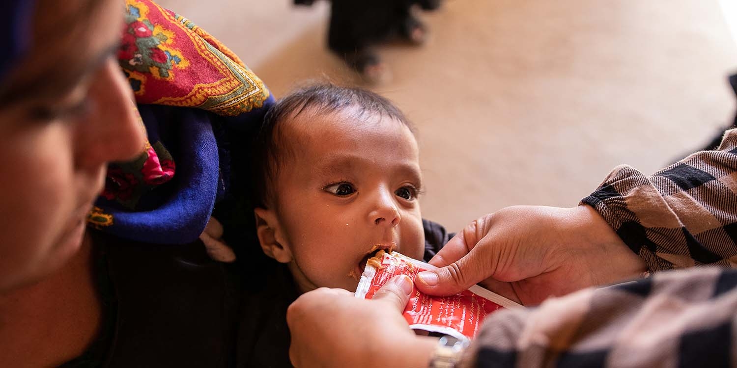 Afghanistan, a worker feeds a baby Plumpy Nut Afghanistan, a worker feeds a baby Plumpy Nut