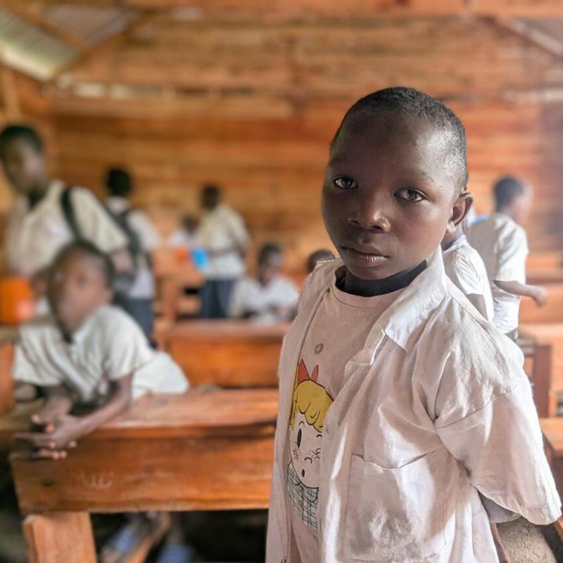 A boy in a white shirt looks at the camera