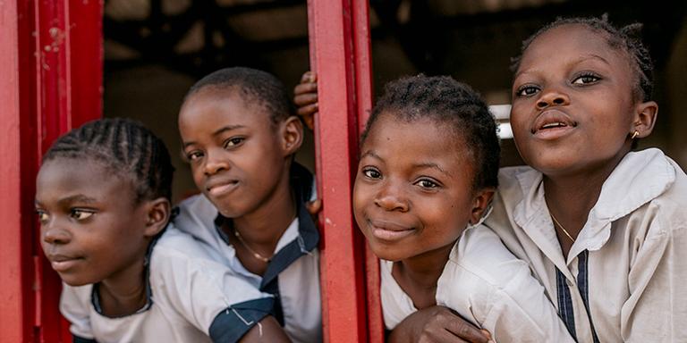Four girls look out a window of a classroom in the DRC Four girls look out a window of a classroom in the DRC