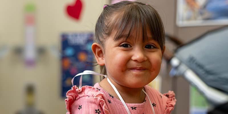 A 3-year-old girl smiles with a holding a handmade ball she made during an early learning class held by Save the Children.