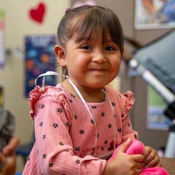 A 3-year-old girl smiles with a holding a handmade ball she made during an early learning class held by Save the Children. A 3-year-old girl smiles with a holding a handmade ball she made during an early learning class held by Save the Children.