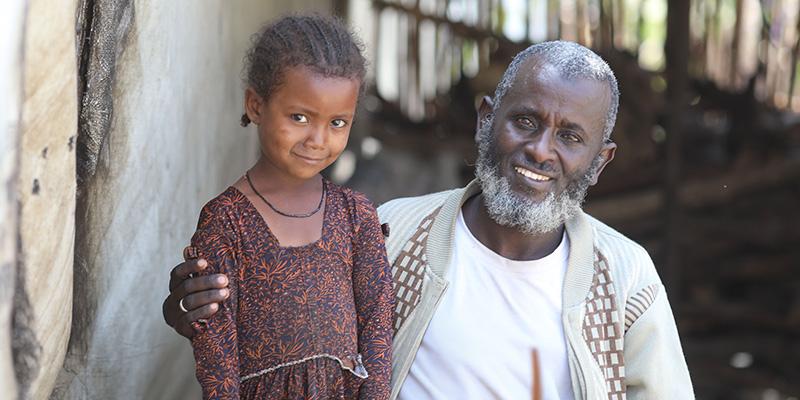 In Ethiopia, a father and daughter sit outside a temporary shelter