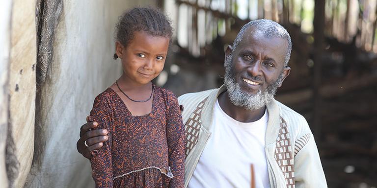 In Ethiopia, a father and daughter sit outside a temporary shelter In Ethiopia, a father and daughter sit outside a temporary shelter