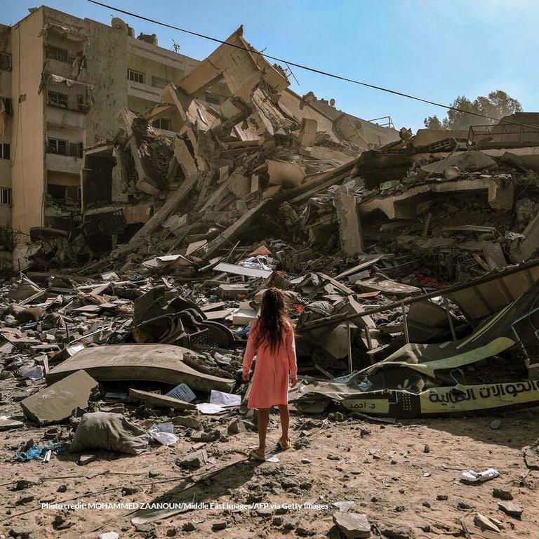 In Gaza, a girl stands in front of a pile of rubble and destroyed buildings. In Gaza, a girl stands in front of a pile of rubble and destroyed buildings.