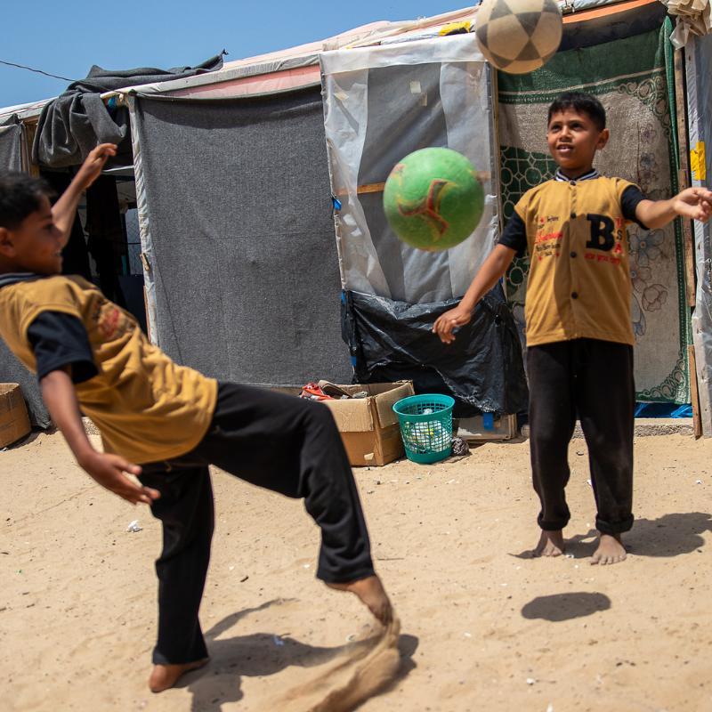 Twin boys, Shadi & Basil, play football close to their tent in Gaza