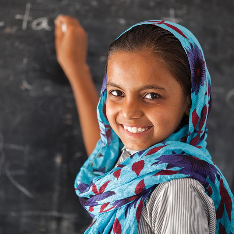 A young girl writes on a chalk board. A young girl writes on a chalk board.