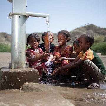 Children gather around a water pump. Children gather around a water pump.