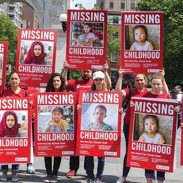 A group of Save the Children voluneers holding up signs that bring attention to children who miss out on childhood. A group of Save the Children voluneers holding up signs that bring attention to children who miss out on childhood.