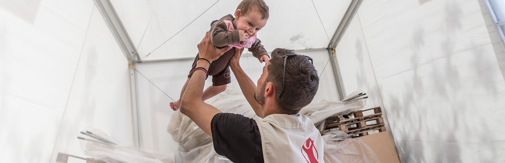 A worker holds a child in a Save the Children tent A worker holds a child in a Save the Children tent