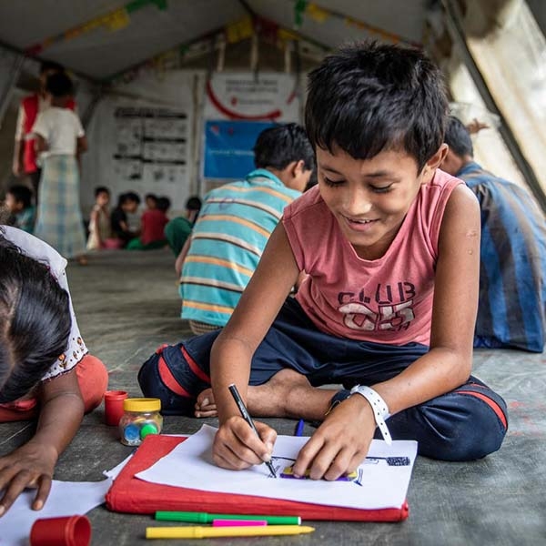 A smiling boy sits on the ground while doing school work. A smiling boy sits on the ground while doing school work.