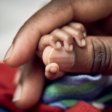 A Ugandan baby’s tiny hand is wrapped around his mother’s thumb. The baby was born a twin and born prematurely – at 7 months – with a birthweight of 1.13 and .95kgs each. The mother is being taught Kangaroo Mother Care, a lifesaving technique that encourages skin-to-skin contact and breastfeeding for premature babies. Photo credit: Juozas Cernius/Save the Children, March 2018. A Ugandan baby’s tiny hand is wrapped around his mother’s thumb. The baby was born a twin and born prematurely – at 7 months – with a birthweight of 1.13 and .95kgs each. The mother is being taught Kangaroo Mother Care, a lifesaving technique that encourages skin-to-skin contact and breastfeeding for premature babies. Photo credit: Juozas Cernius/Save the Children, March 2018.