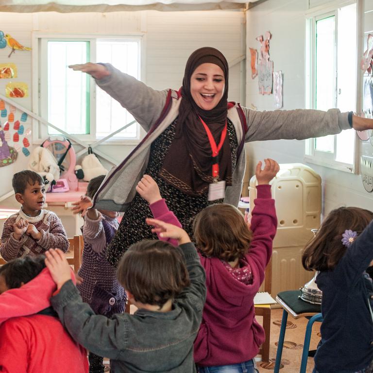 A kindergarten teacher leads her students in a music activity at a Save the Children Rainbow Kindergarten for refugee children. Every classroom runs a Healing and Education Through the Arts (HEART) activity daily. Photo credit: Susan Warner/Save the Children, December 2016. A kindergarten teacher leads her students in a music activity at a Save the Children Rainbow Kindergarten for refugee children. Every classroom runs a Healing and Education Through the Arts (HEART) activity daily. Photo credit: Susan Warner/Save the Children, December 2016.