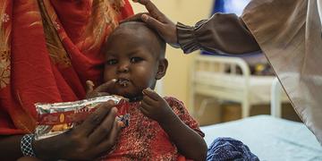 Saadia*, 21, feeding food paste to her daughter Aisha*, 2, as part of her treatment for malnutrition, Wajir, Kenya. Saadia*, 21, feeding food paste to her daughter Aisha*, 2, as part of her treatment for malnutrition, Wajir, Kenya.
