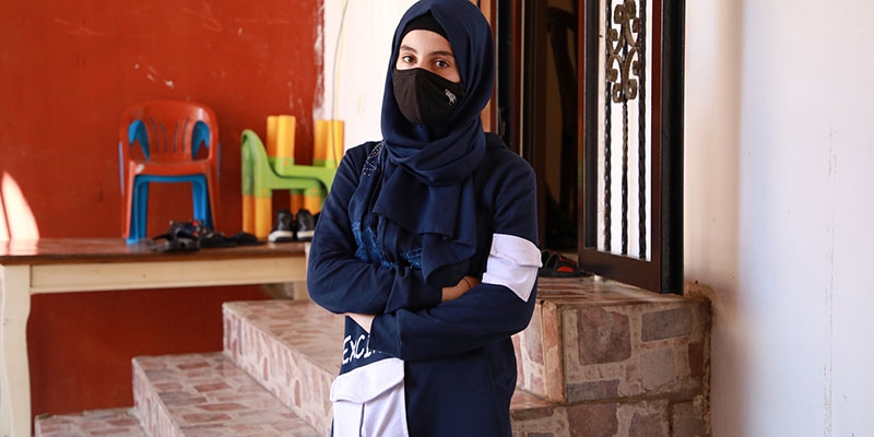 Mariam stands in front of a set of stone steps with her arms cross, facing the camera. Mariam stands in front of a set of stone steps with her arms cross, facing the camera.
