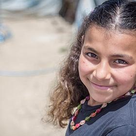 An 11-year old girl smiles while standing in an informal tented settlement in the Bekaa Valley, Lebanon. An 11-year old girl smiles while standing in an informal tented settlement in the Bekaa Valley, Lebanon.