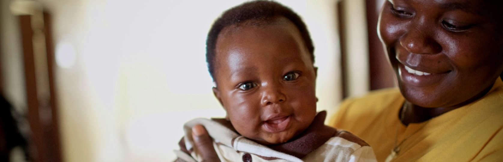 A mother smiles as she holds her 3-month old child at a Save the Children-supported clinic in Louisiana, Montserrado county, Liberia. In 2013, Save the Children raised $500,000 to build six new health facilities in some of the poorest and most remote health districts across two counties of Liberia. These health clinics are providing vital, life-saving medical services to the 40,300 people who currently have limited access to any kind of proper healthcare. Photo credit: Magda Rakita/Save the Children, Januar A mother smiles as she holds her 3-month old child at a Save the Children-supported clinic in Louisiana, Montserrado county, Liberia. In 2013, Save the Children raised $500,000 to build six new health facilities in some of the poorest and most remote health districts across two counties of Liberia. These health clinics are providing vital, life-saving medical services to the 40,300 people who currently have limited access to any kind of proper healthcare. Photo credit: Magda Rakita/Save the Children, Januar