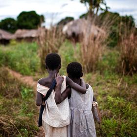 Two young sisters who lost their mother to HIV and AIDS walk home arm-in-arm after school. Photo credit: Save the Children, 2010. Two young sisters who lost their mother to HIV and AIDS walk home arm-in-arm after school. Photo credit: Save the Children, 2010.