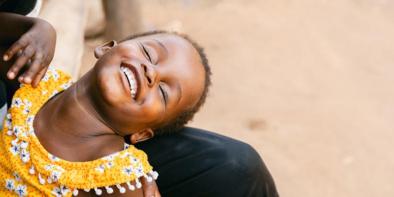 In Malawi, a young girl laughs and closes her eyes