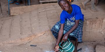 Mali, a girl in a blue t-shirt washes her hands and smiles at the camera Mali, a girl in a blue t-shirt washes her hands and smiles at the camera