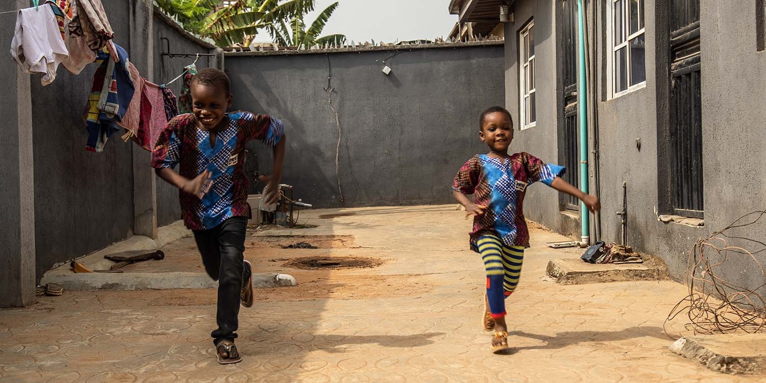 Nigeria, a young brother and sister run together Nigeria, a young brother and sister run together