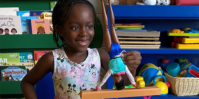 A little girl plays with a Barbie doll from Mattel. Mattel and Save the Children have partnered together for over 15 years.