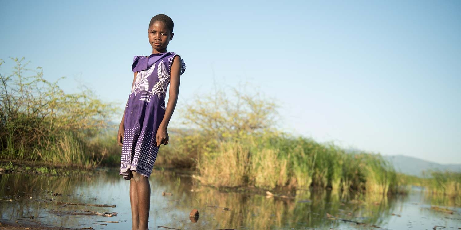 Malawi, a little girl in a purple dress on a boat, smiles at the camera Malawi, a little girl in a purple dress on a boat, smiles at the camera