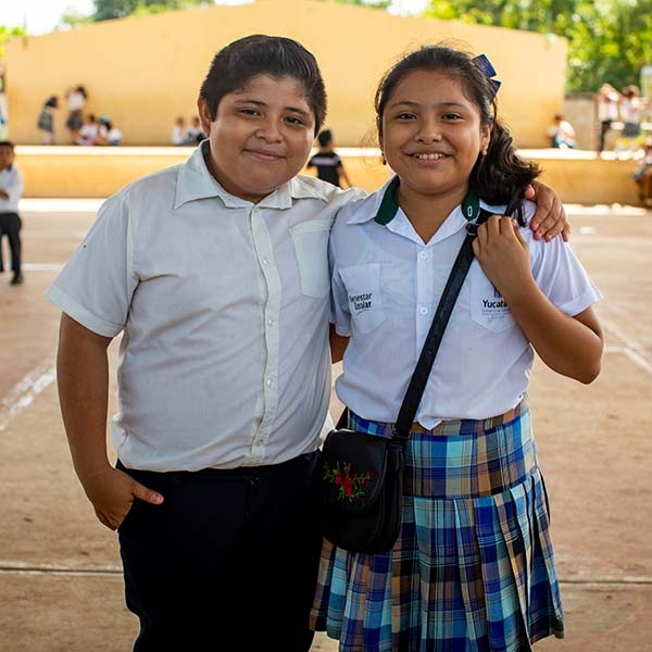 Two school children stand next to one another outside a school in Mexico. Two school children stand next to one another outside a school in Mexico.