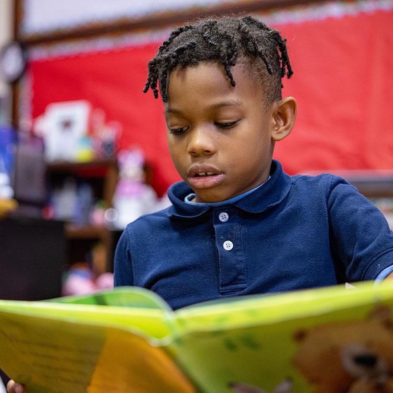 Mississippi, an 8-year-old boy in a navy-blue shirt reads with Grandma Chestnut in the Save the Children room.