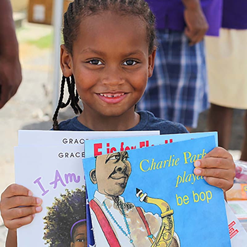 Mississippi, little boy with corn rows holds up children's boos he received at a Save the Children literacy event. Mississippi, little boy with corn rows holds up children's boos he received at a Save the Children literacy event.