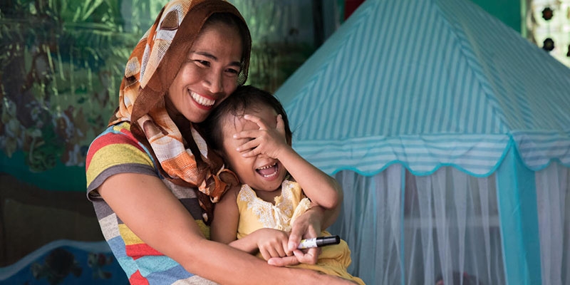 A mother holds her small child while smiling and laughing A mother holds her small child while smiling and laughing