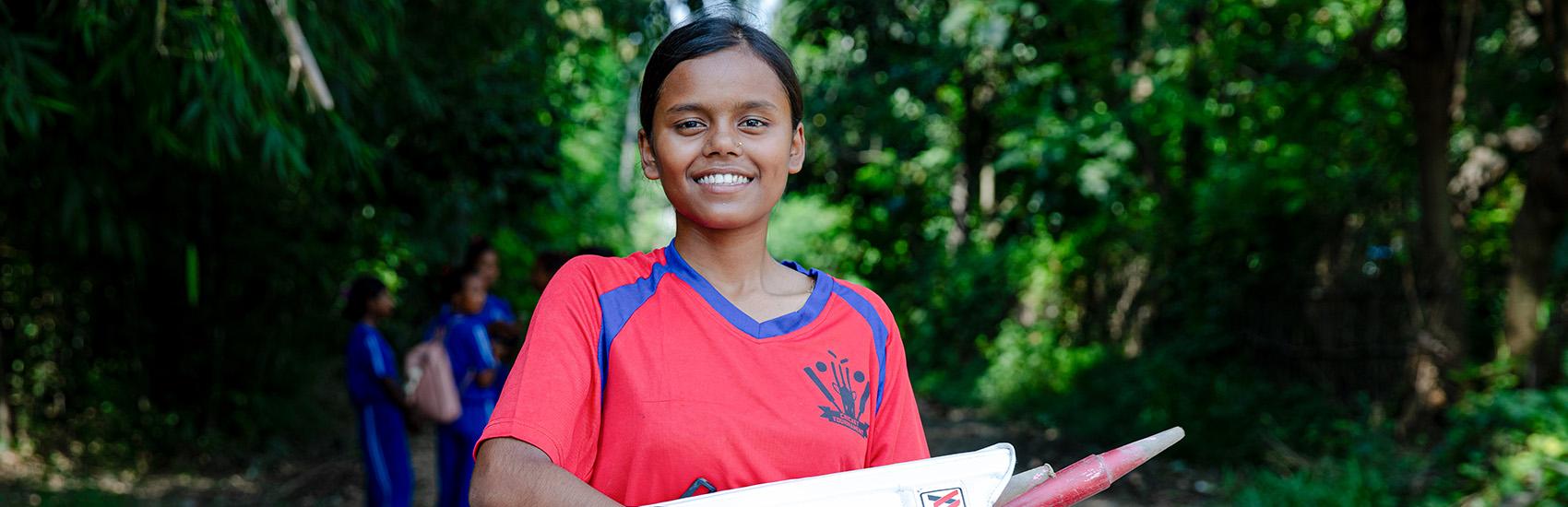 A teenage girl carries cricket gear and prepares for a match in Nepal A teenage girl carries cricket gear and prepares for a match in Nepal