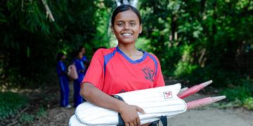 A teenage girl carries cricket gear and prepares for a match in Nepal A teenage girl carries cricket gear and prepares for a match in Nepal