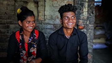 A teenage boy and girl sitting next to each other and smiling. A teenage boy and girl sitting next to each other and smiling.
