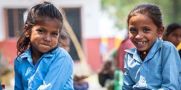 A girl in a blue shirt smiles at the camera.