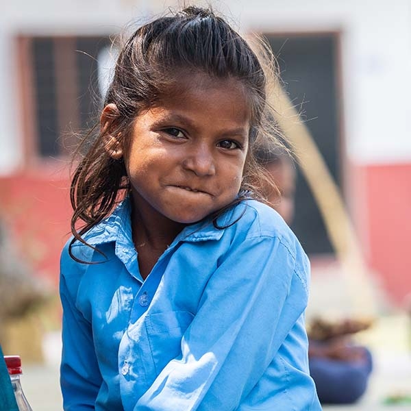 A girl in a blue shirt smiles at the camera. 