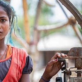 Nepal, a girl in orange stands outside of her family home Nepal, a girl in orange stands outside of her family home