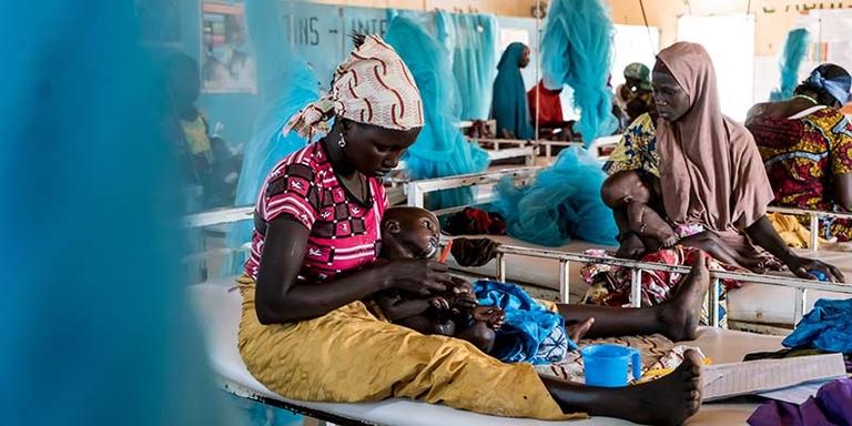South Sudan, a woman in a red and black dress looks away from the camera South Sudan, a woman in a red and black dress looks away from the camera