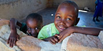 Two children look out the "window" at the Early Childhood Center in a village in Zimbabwe. Photo Credit: Eileen Burke/Save the Children 2011. Two children look out the "window" at the Early Childhood Center in a village in Zimbabwe. Photo Credit: Eileen Burke/Save the Children 2011.