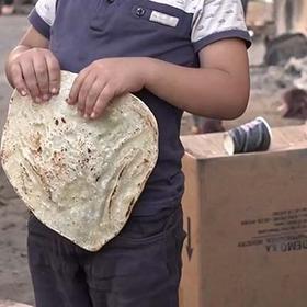 A young boy holds some bread on a street in North Gaza. A young boy holds some bread on a street in North Gaza.